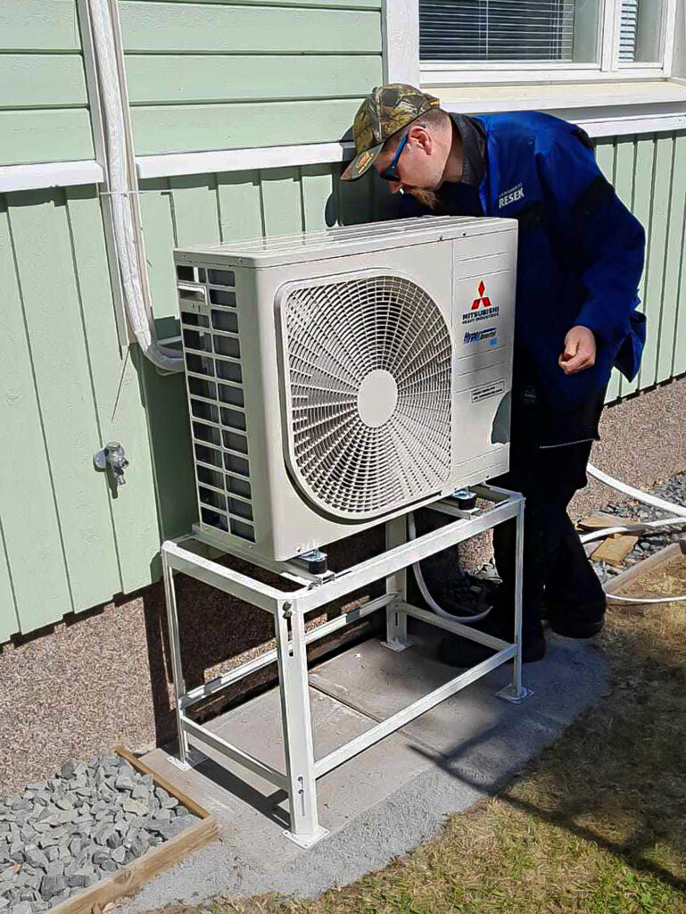 Ilmalämpöpumppujen asentaja asentamassa ulkoyksikköä.